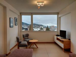 - un salon avec une grande fenêtre, une table et des chaises dans l'établissement Amanecer en el Lago, à San Carlos de Bariloche