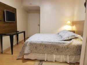 a bedroom with a bed and a desk and a television at KIKO in Tramandaí