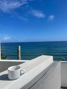 una tazza di caffè seduta su un cornicione che si affaccia sull'oceano di The Sea Cliff Hotel Resort & Spa a Port Antonio