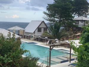 a swimming pool next to a house and the ocean at The Sea Cliff Hotel Resort & Spa in Port Antonio