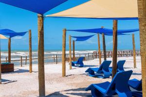 una playa con sillas y sombrillas azules en Makai Resort All Inclusive Convention Aracaju, en Aracaju