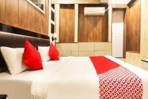 a bedroom with a bed with red and white pillows at Hotel Sheela in Rohtak