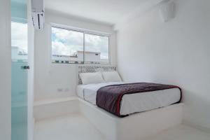 um quarto branco com uma cama e uma janela em Italia Estación Hotel, Merida em Mérida
