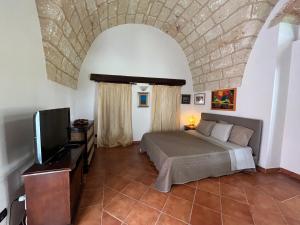 a bedroom with a bed and a flat screen tv at Villa Emanuel in Alessano