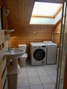 uma casa de banho com uma máquina de lavar roupa e um lavatório em Le Chalet de la REPANDISE em Laveline-du-Houx