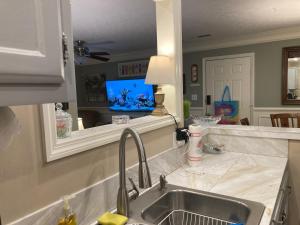 a kitchen with a sink and a tv in a mirror at Classic City 3 bedroom 2 bath condo with deck close to UGA, Five Points, and Memorial Park in Athens in Athens