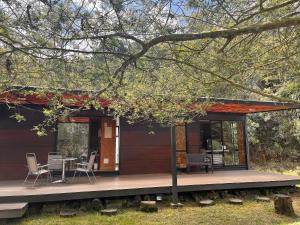 uma pequena casa com um alpendre, uma mesa e cadeiras em Refugio de la Montaña en el Alto del Escobero em El Retiro