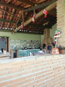 an outdoor kitchen with a brick wall and a fireplace at Casa - Sítio da Tabi - Lagoinha-SP in Lagoinha