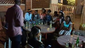 un gruppo di persone seduti intorno ai tavoli con bevande di TERRANOVAH APARTMENT a Nyagatare