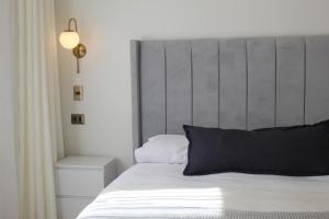 a bedroom with a white bed with a gray headboard at Hotel Marcos Gamero in Talca