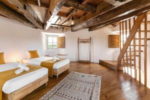 Dos camas en una habitación con techos de madera. en Moinho do Sr. Arnaldo, en Atouguia da Baleia