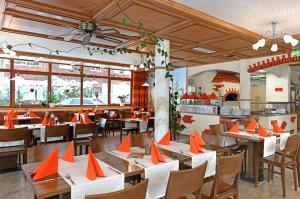 ein Restaurant mit Tischen und Stühlen mit orangefarbenen Kegeln darauf in der Unterkunft Tre Soli Appartements Restaurant in Schoppernau