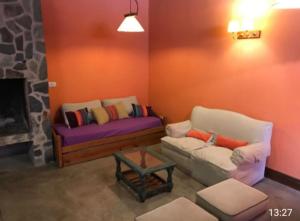 sala de estar con 2 sofás y chimenea en Casa El Cobijo en Tandil