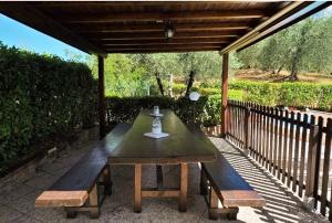 une table et des bancs en bois sous une pergola en bois dans l'établissement Podere Il Leccione, à Palaia