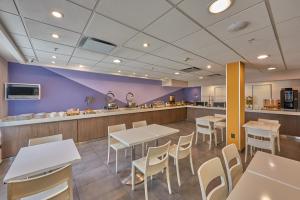 a restaurant with white tables and chairs and purple walls at Sierra Suites By HP Hotels in San Luis Potosí