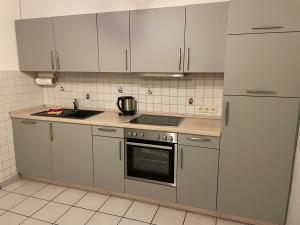 una cocina con electrodomésticos de acero inoxidable y armarios blancos en Fewo Alte Schule, en Willingen