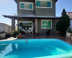 a house with a swimming pool in front of a house at Região dos Lagos Casa de Campo in São Pedro da Aldeia