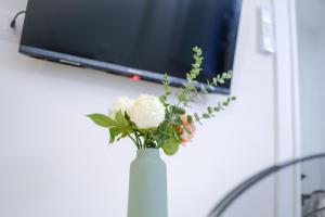 a white vase with a white rose in front of a tv at Le Dantesche Boutique Apartments in Florence