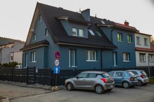 維斯瓦的住宿－Apartamenty Wisła Centrum，一座蓝色的房子,前面有汽车停放