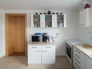 een keuken met witte kasten en een magnetron bij Ferienwohnung im bayerischen Wald in Tittling