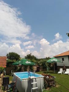 a pool with an umbrella and chairs and a table with at Събевата къща in Sinʼo Bŭrdo