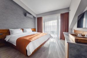 um quarto de hotel com uma cama e uma grande janela em Ivy Hotel em Tbilisi