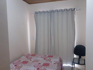 a bedroom with a bed and a chair and a curtain at Casa em Torres Praia da Cal in Torres