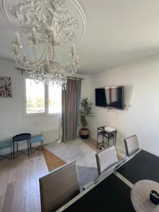 een woonkamer met een kroonluchter en een tafel en stoelen bij Très joli appartement mignon confortable à Paris Villeneuve-la-Garenne in Villeneuve-la-Garenne