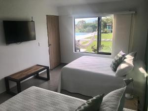 a hotel room with two beds and a television at Torcaza Casa de Campo in Quimbaya