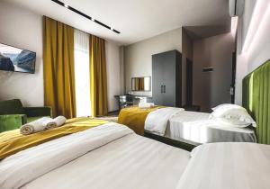 ein Hotelzimmer mit 3 Betten und gelben Vorhängen in der Unterkunft Nord Hotel Boutique in Shkodra