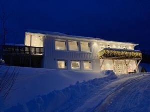 una casa con luces encendidas en la nieve por la noche en Fantastic view, quiet and relaxing by the sea en Kvaløya