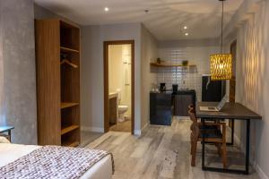 a bedroom with a bed and a desk and a kitchen at Kastel Petrópolis in Petrópolis