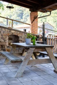 a wooden picnic table on a patio with a fireplace at Apartamentos Rurales Villa-García in Corigos