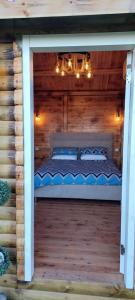 uma cama num chalé de madeira com um lustre em מפגש הדובדבן em Buq‘ātā mais 21 fotografias