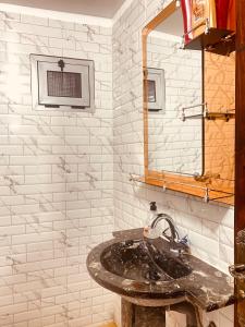 een badkamer met een wastafel en een spiegel bij Hôtel Bia Besta in Boumalne