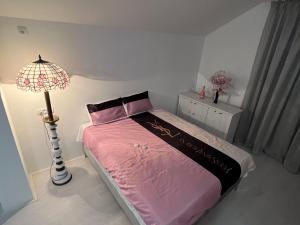 una camera da letto con un letto con lenzuola rosa e una lampada di Infinity a Novi Sad