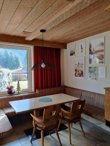a dining room with a table and chairs and a window at Alpinum Hostel in Biberwier