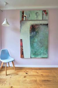 una habitación con una silla azul y una pintura en la pared en hej atelier Ferienwohnung, en Heiligenthal