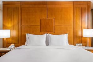 a bedroom with a large white bed with a wooden headboard at Meliá Brasil 21 in Brasilia