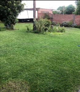 un patio con césped verde y una pared de ladrillo en CASA EN VILLA DE MERLO ( san Luis ) en Merlo