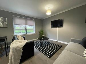 a living room with a couch and a tv at Dunbeth House in Coatbridge