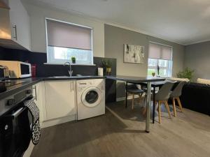 a kitchen with a washing machine and a table with chairs at Dunbeth House in Coatbridge