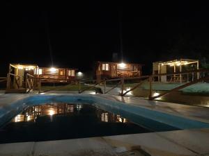 a swimming pool at night with lodges in the background at Cabañas Samay in Casa Grande
