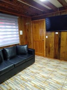 a living room with a black couch and a door at Cabañas El_Nativo2 in Choshuenco