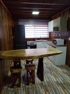 a kitchen with a large wooden table and stools at Cabañas El_Nativo2 in Choshuenco