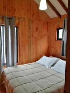 a bedroom with a large bed in a wooden wall at Cabañas El_Nativo2 in Choshuenco +28 photos