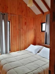 a bedroom with a large bed in a wooden wall at Cabañas El_Nativo2 in Choshuenco