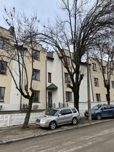 two cars parked on a sidewalk in front of buildings at Leo Rooms in Lviv