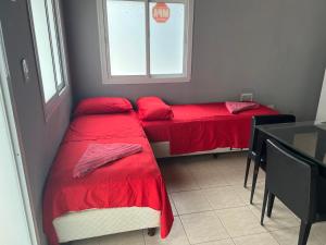 two beds in a room with a table and a window at Cerro Arco Apart Hotel in El Challao