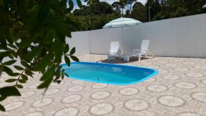 a swimming pool with two chairs and an umbrella at CHALÉ ESTÂNCIA OURO VERDE in Lages